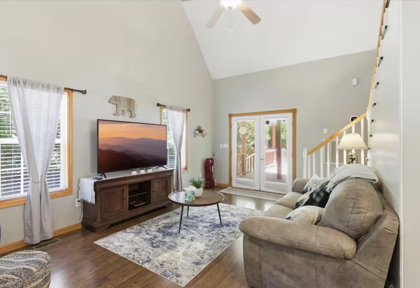 Vaulted great room with sofa, TV and doors to the deck