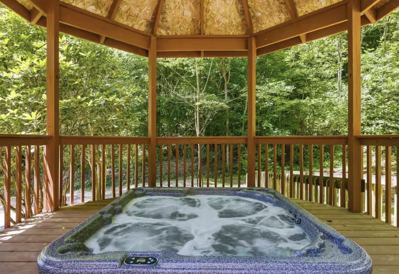 Hot tub set inside a wooden gazebo surrounded by trees