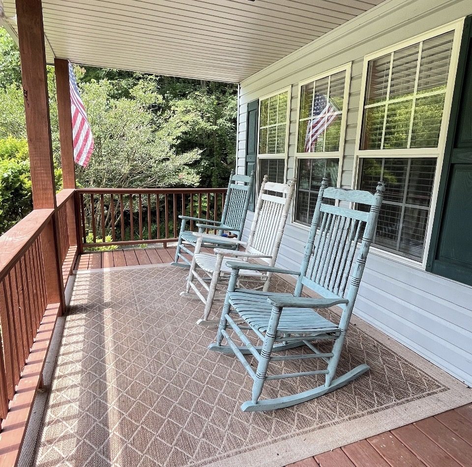 Covered front porch with rocking chairs and an American flag